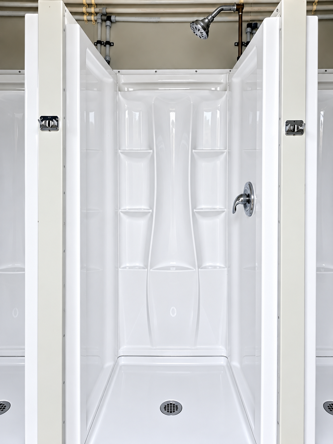 White shower stall with a shower head and floor drain
