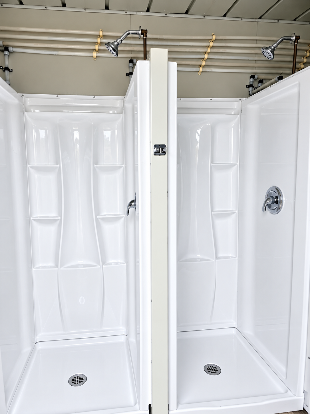 Two white shower stalls with wall mounted shower heads